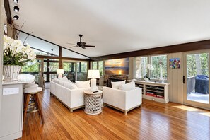 Ein modernes Wohnzimmer mit einer Couch, zwei Beistelltischen, einem Deckenventilator und einem Kamin.