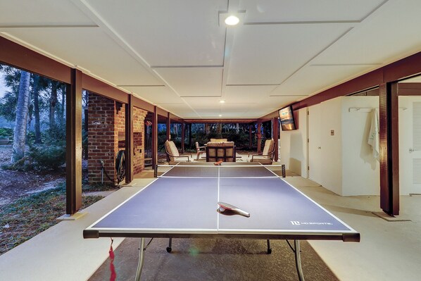 Una mesa de ping pong en una habitación con vistas a un bosque.