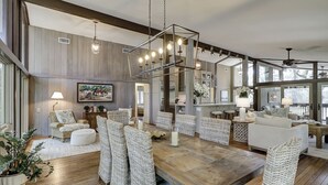 Un vaste salon doté d’une table à manger en bois, de chaises en osier et d’un lustre moderne.