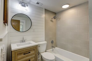 Un baño con lavabo, espejo, inodoro y bañera.