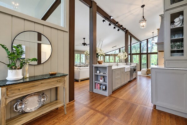 A spacious kitchen with a large island, wooden flooring, and a view of the outdoors.