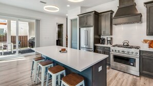 A modern kitchen with a central island, stainless steel appliances, and a large window overlooking a patio. - Luxe 4BR 30A Retreat w/ Private Pool & Golf Cart (Santa Rosa Beach)
