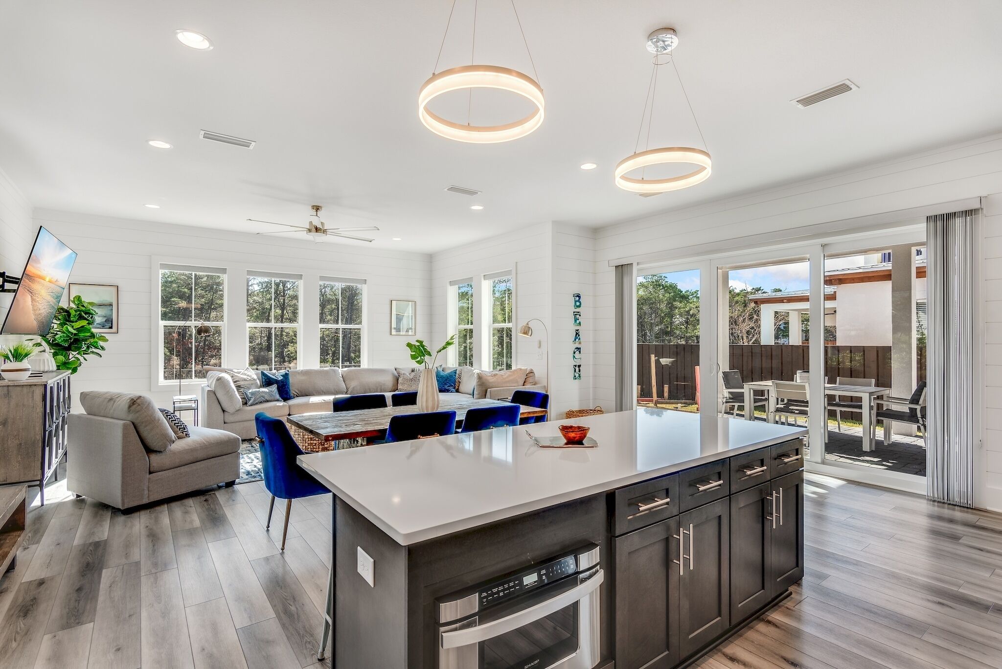 A spacious kitchen with a central island, dark cabinetry, and a modern pendant light fixture.