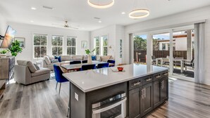 A spacious kitchen with a central island, dark cabinetry, and a modern pendant light fixture. - Luxe 4BR 30A Retreat w/ Private Pool & Golf Cart (Santa Rosa Beach)