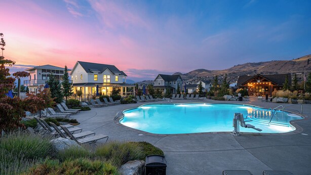A swimming pool with lounge chairs, a building with multiple windows, and a mountainous backdrop. - Welcome to Skylake Cottage at The Lookout at Lake Chelan (Chelan)