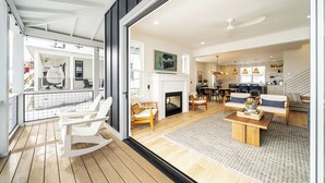 A spacious living area with a fireplace, wooden flooring, and a balcony with a rocking chair. - Welcome to Skylake Cottage at The Lookout at Lake Chelan (Chelan)