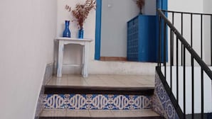 Uma escadaria com ladrilhos estampados leva a um quarto com porta azul.