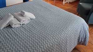 Um quarto com cama, escrivaninha, cadeira e espelho.