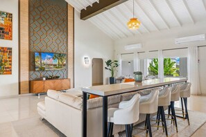 Una cocina moderna con una isla central, taburetes de bar y un área de comedor con sofá.