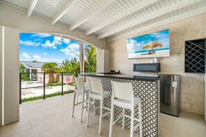 A kitchen area with a bar, white chairs, a refrigerator, and a TV mounted on the wall. - Ocean Front! 8BR Villa with Pool near Malmok Beach (Malmok)