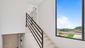 A staircase with a black railing leading to a door, a large window with a view of a landscape, and a light switch on the wall. - Ocean Front! 8BR Villa with Pool near Malmok Beach (Malmok)