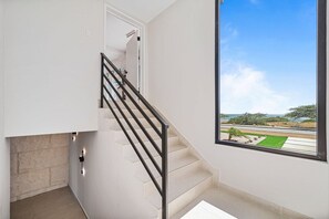 A staircase with a black railing leading to a door, a large window with a view of a landscape, and a light switch on the wall. - Ocean Front! 8BR Villa with Pool near Malmok Beach (Malmok)
