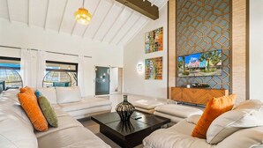 A modern living room with a sofa set, a coffee table, and a television mounted on a wooden panel. - Ocean Front! 8BR Villa with Pool near Malmok Beach (Malmok)