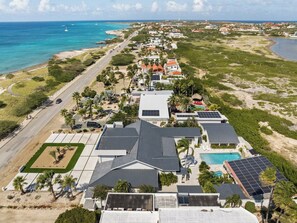 Une propriété située sur la côte, comprenant plusieurs bâtiments, une piscine et des panneaux solaires.