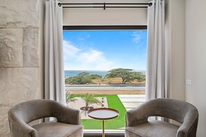 A room with a view of a coastal landscape, two chairs, and a small table. - Ocean Front! 8BR Villa with Pool near Malmok Beach (Malmok)