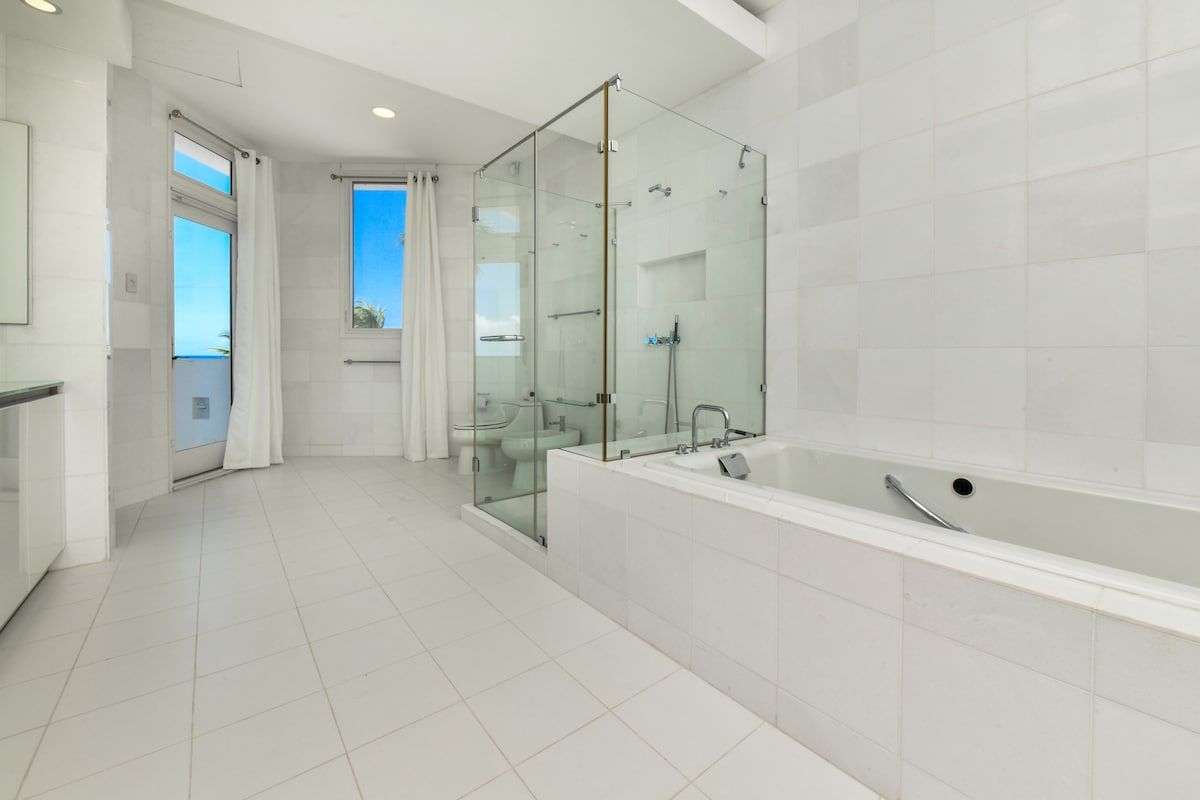 A modern bathroom with a glass-enclosed shower, a large bathtub, and a toilet.