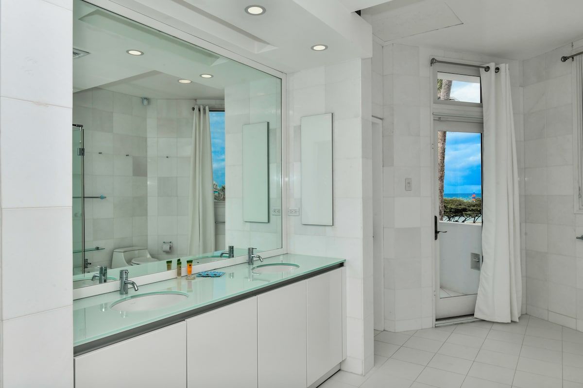 Une salle de bain moderne avec deux lavabos, un grand miroir et un espace douche avec vue.