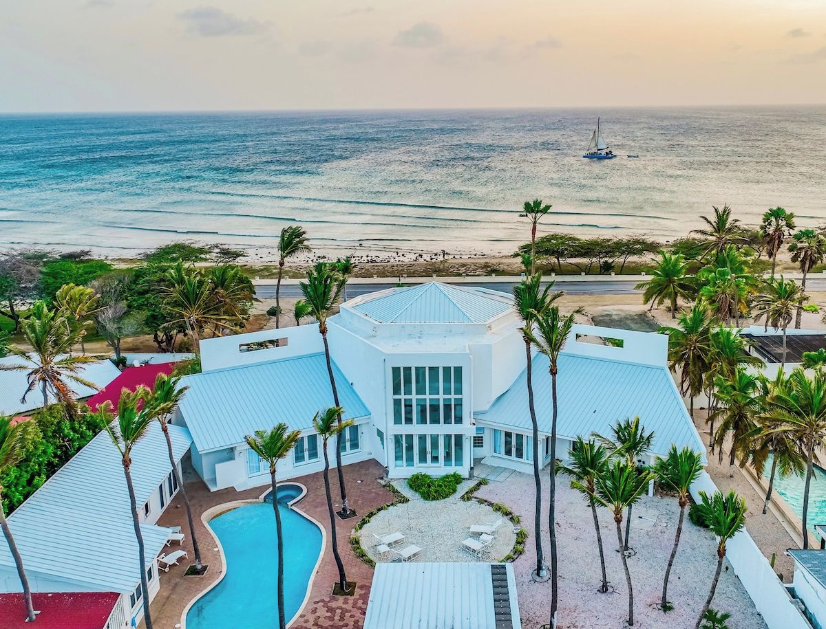 Un resort con piscina, palmeras y vista al océano.