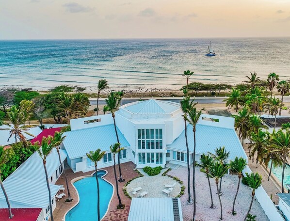 Un resort con piscina, palmeras y vista al océano.