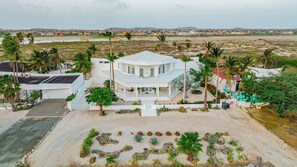 A large, modern house with a central patio, surrounded by palm trees and a view of a distant landscape. - Oceanfront 8BR Villa w/ Pool & Patio, Malmok (Malmok)