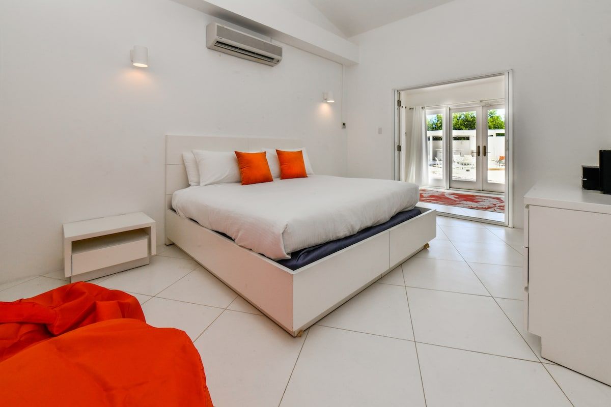 Un dormitorio moderno con una cama grande, una mesita de noche y un ventanal corredero que da a un área exterior.