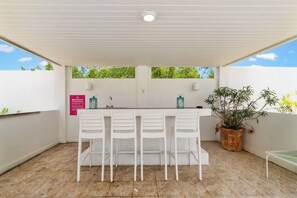 An outdoor patio with a white bar and four white chairs. - Oceanfront 8BR Villa w Pool, Patio near Palm Beach (Malmok)