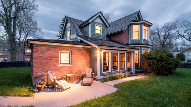 A two-story house with a brick exterior, a covered porch, and a large window.