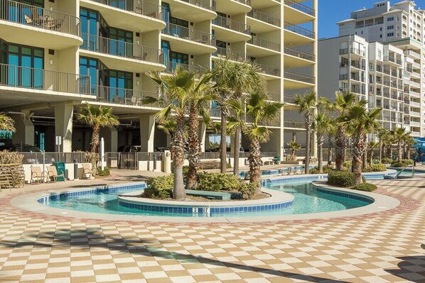 A hotel with a pool area surrounded by palm trees and a checkered floor.