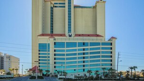Um hotel grande com uma torre central e vários andares, apresentando uma entrada notável e uma vista clara da região circundante.