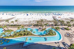 A beach resort with a swimming pool, beach umbrellas, and palm trees.