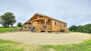 Una baita di legno con veranda, vialetto sterrato e area verde.