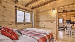 Interno di una baita in legno con un letto, un'area pranzo e una cucina.