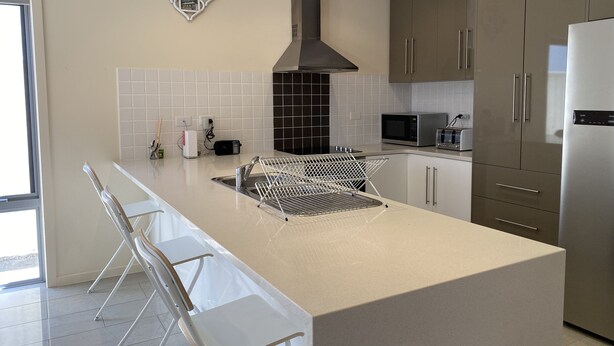 A modern kitchen with a central island, stainless steel appliances, and a tiled backsplash.