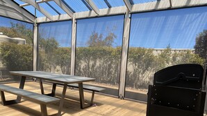 A covered patio area with a picnic table and grill.