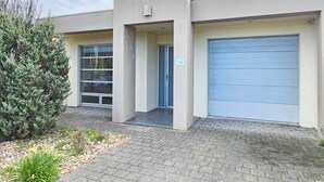 A building with a modern architectural style, featuring a central entrance with a glass door and a blue garage door.