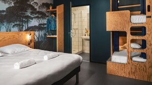 Moderni hotellihuone, jossa on suuri sänky, puinen kerrossänky, kylpyhuone, jossa on pesuallas ja peili, sekä seinällä oleva suuri seinämaalaus, jossa on kuvattuna puita.