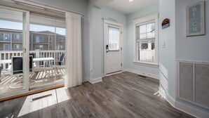 A spacious room with a large sliding glass door leading to a balcony, a white door, and a window with blinds. - WALK TO BEACH -  5 BR, DOG-FRIENDLY BEAUTY - 101 SWEDES ST, DEWEY BEACH (Dewey Beach)