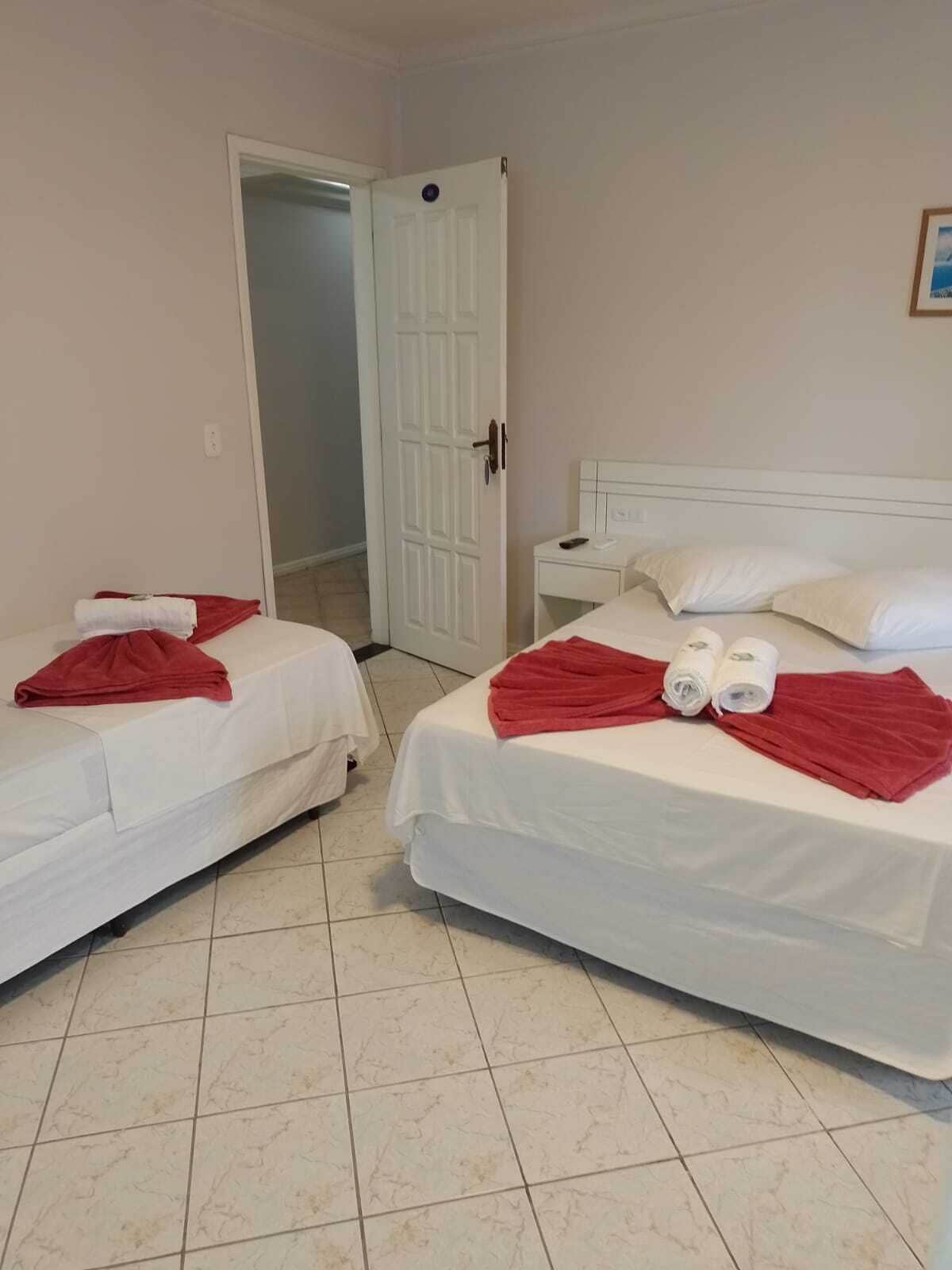 Habitació d'hotel amb dos llits, cadascun amb roba de llit blanca i tovalloles vermelles. Hi ha una tauleta de nit amb un telèfon i una taula petita al costat dels llits.