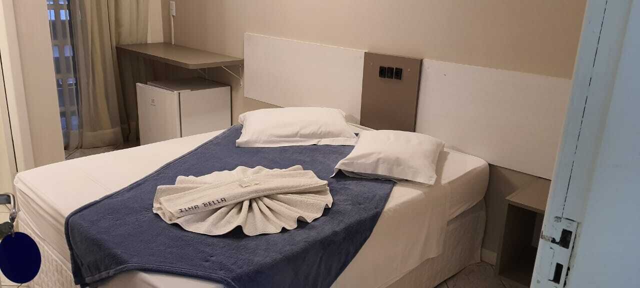 A hotel room with a bed, two pillows, a bedside table, and a nightstand.
