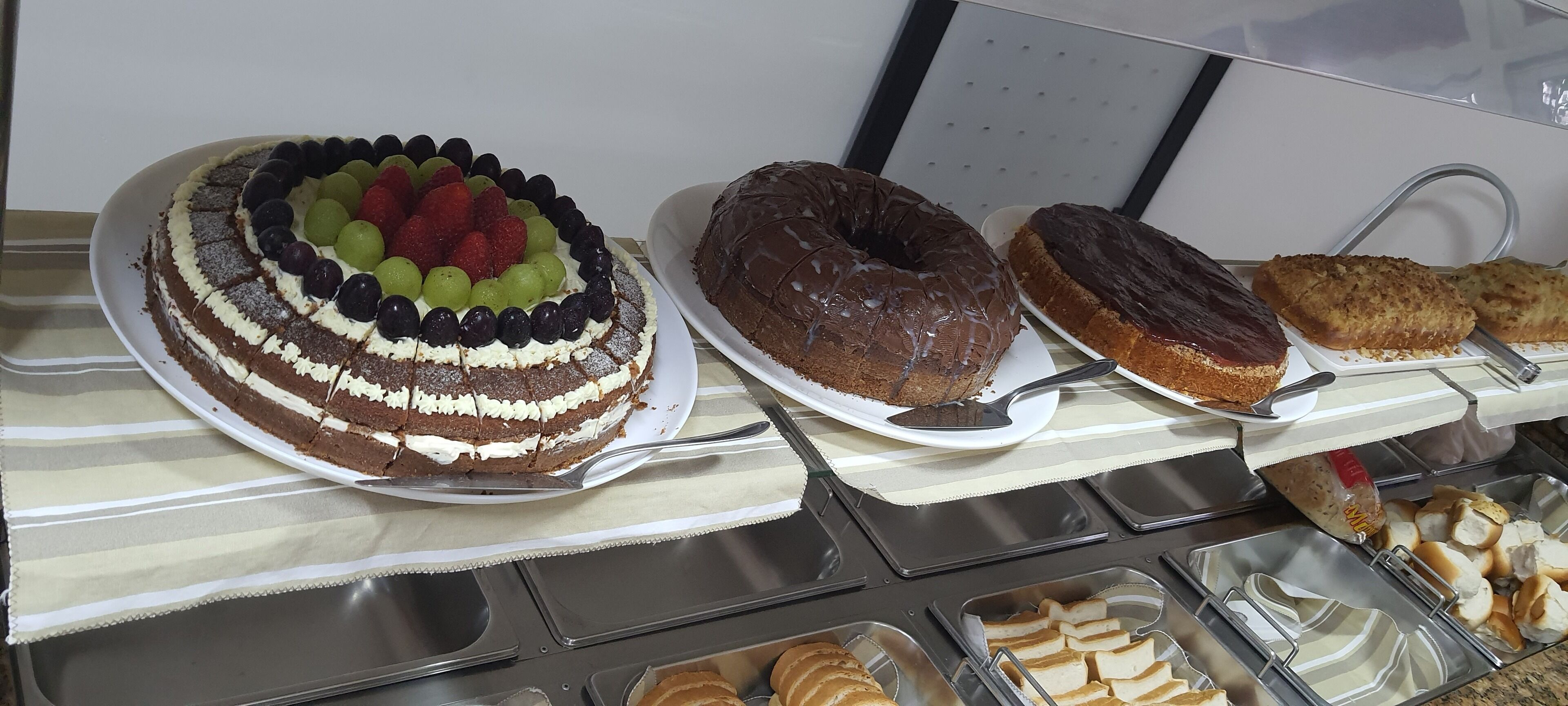 Un bufé con una variedad de postres, incluyendo un pastel en capas, rosquillas de chocolate y pastelería.