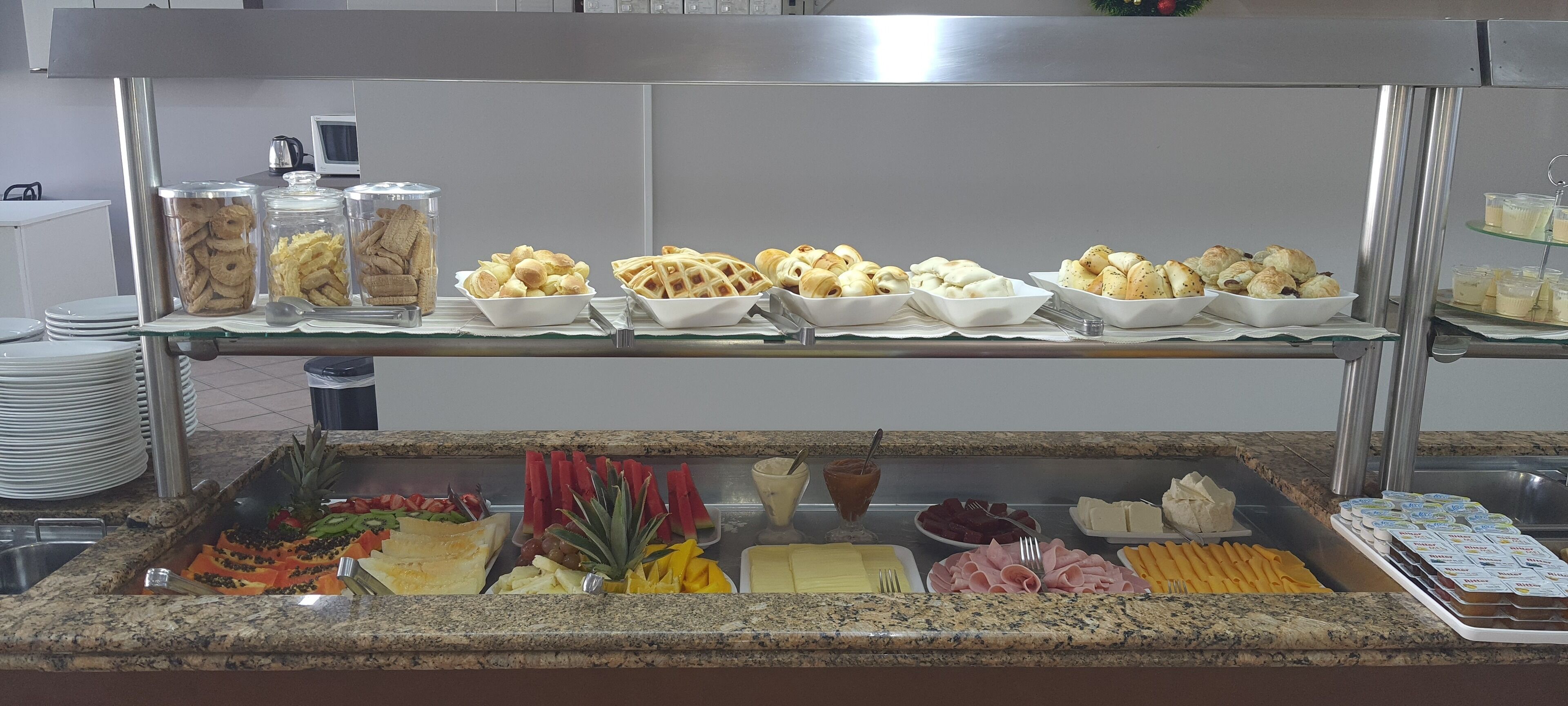 Un bufé con diversas opciones de comida, incluyendo frutas, pasteles y productos lácteos.