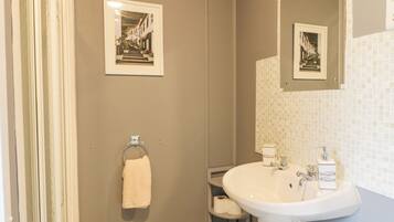 Une salle de bain équipée d’un lavabo, d’un miroir, d’un porte-serviettes et de deux tableaux encadrés accrochés au mur.