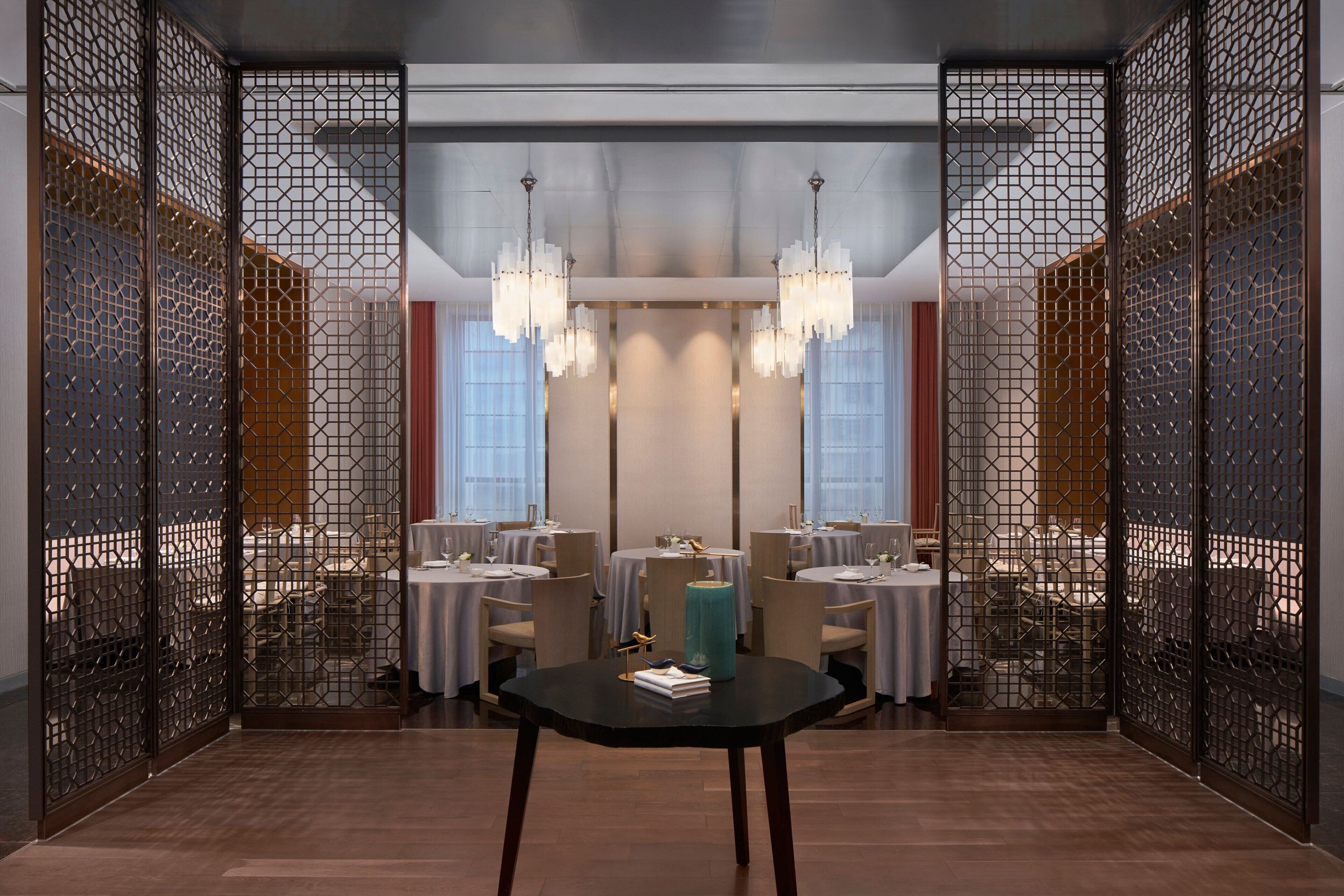 A modern dining area with a central table, multiple chairs, and decorative lighting.