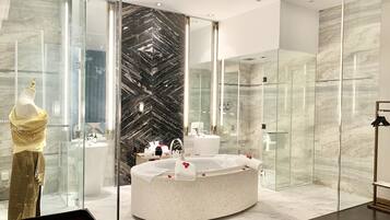 A modern bathroom with a large mirror, a freestanding bathtub, and a glass shower enclosure.