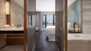A modern hotel room with a large bed, a bathroom with a vanity, and a view of the city through large windows. - The Westin Haikou (Haikou)