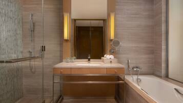 A modern bathroom with a glass shower enclosure, a large mirror, a bathtub, and wooden cabinetry.