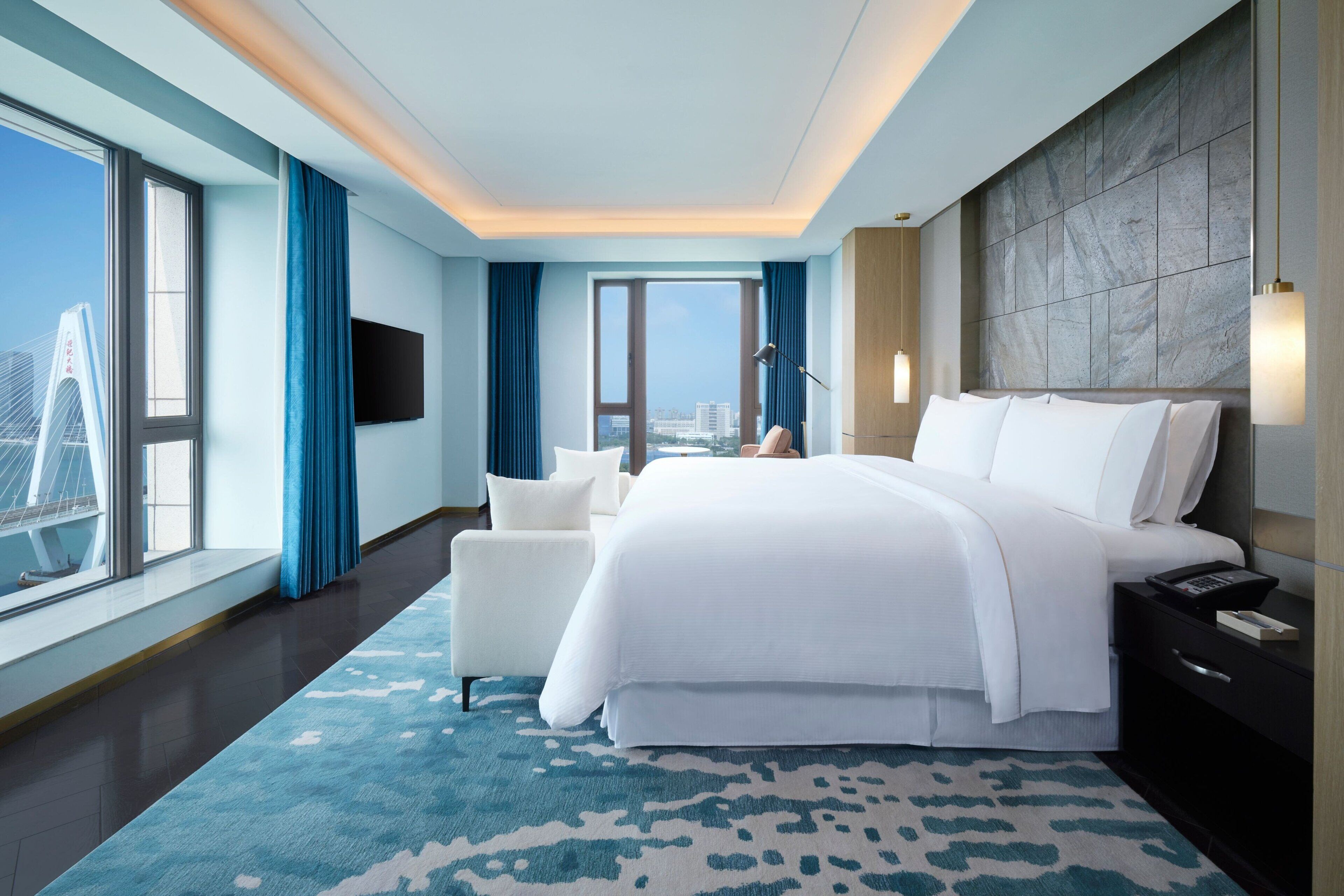 Une chambre d’hôtel moderne, dotée d’un grand lit, d’un canapé, d’un bureau et offrant une vue sur la ville.