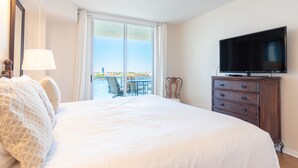 A hotel room with a large bed, a television, a dresser, and a view of the outdoors. - Bright & Spacious Condo with Breathtaking Bay Views + WiFi (Sunny Isles Beach)