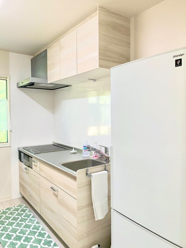 A compact kitchen with a built-in stove, a sink, and a white refrigerator.