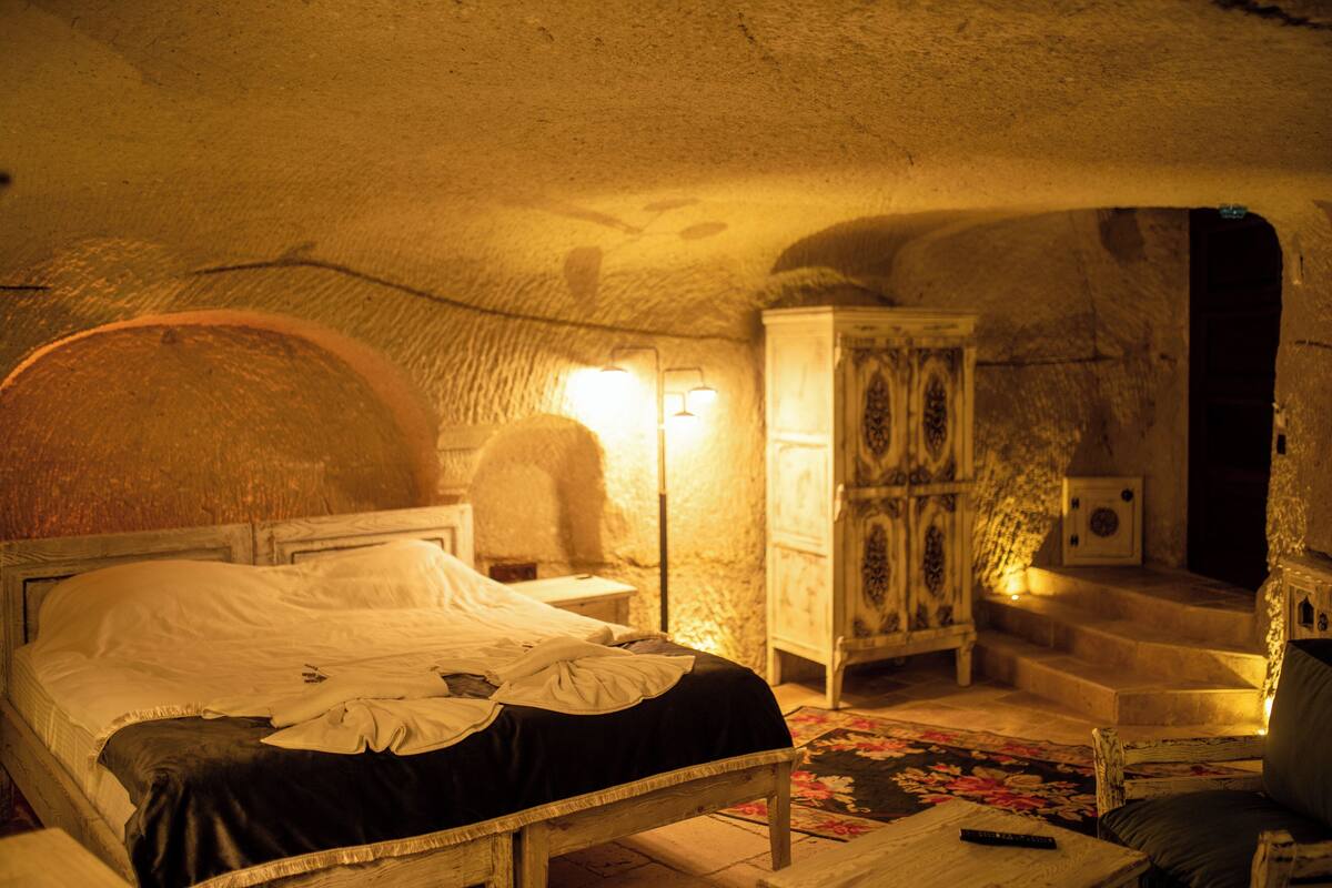 A cozy room with a bed, a nightstand, a cabinet, and a chair.